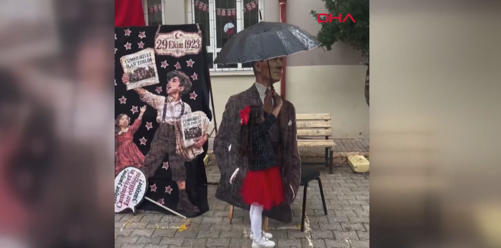 Atatürk maketini yağmurdan şemsiyeyle korudu
